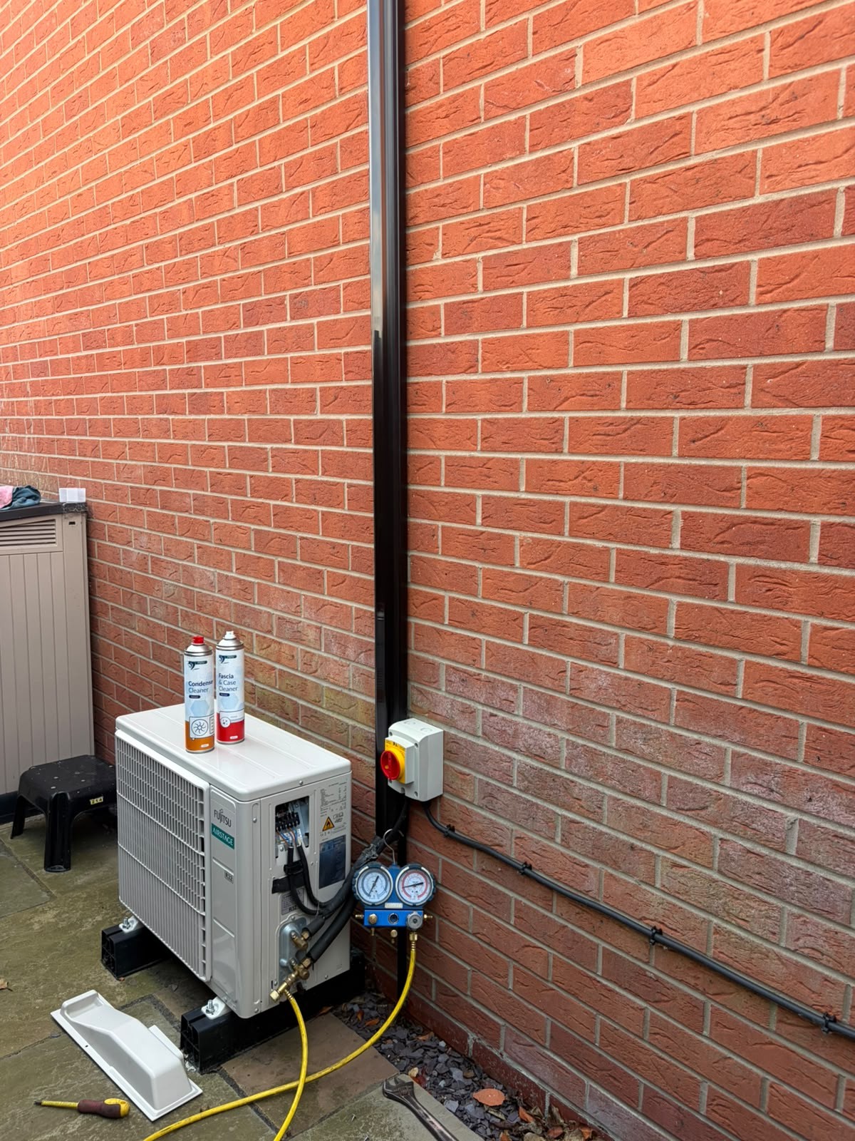 Air conditioning maintenance service with condenser cleaner and refrigerant gauges on a Fujitsu outdoor unit