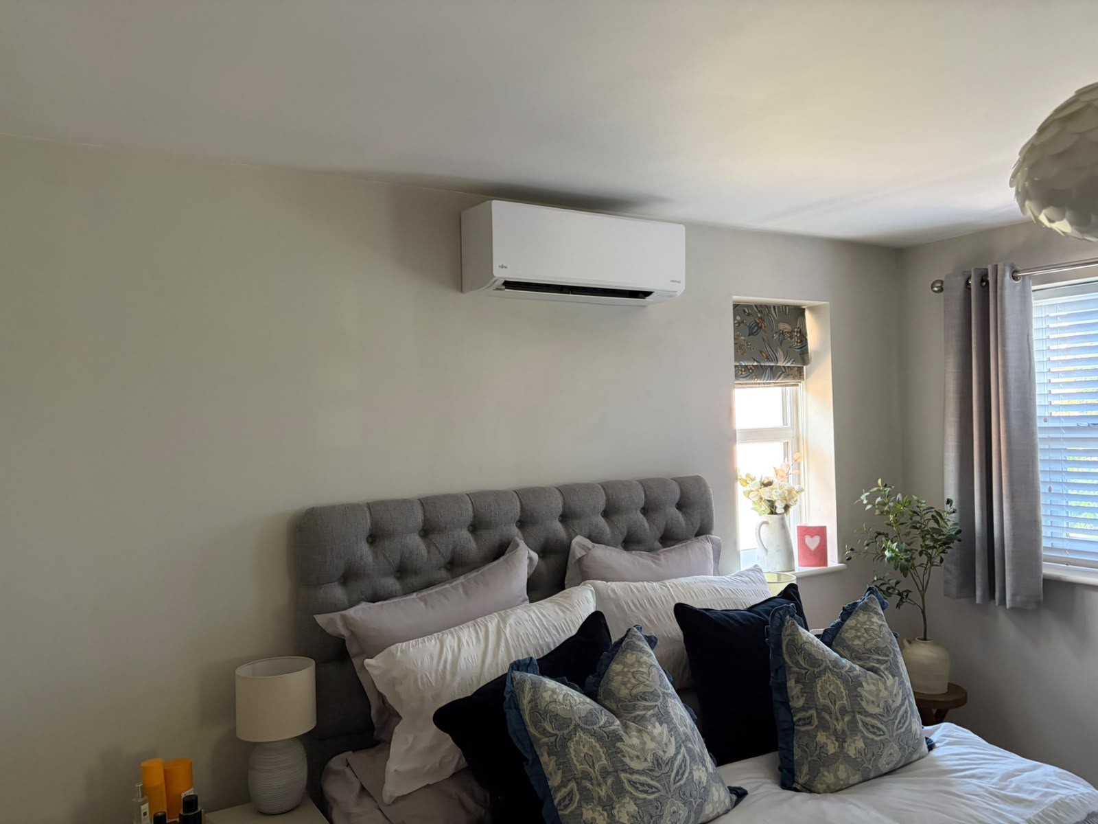 Domestic air conditioning wall unit installed above a bed in a home bedroom