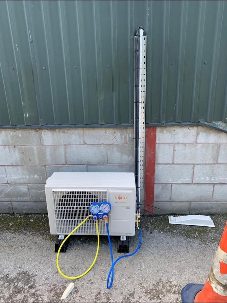 New Fujitsu air conditioning outdoor unit being commissioned with refrigerant gauges after installation